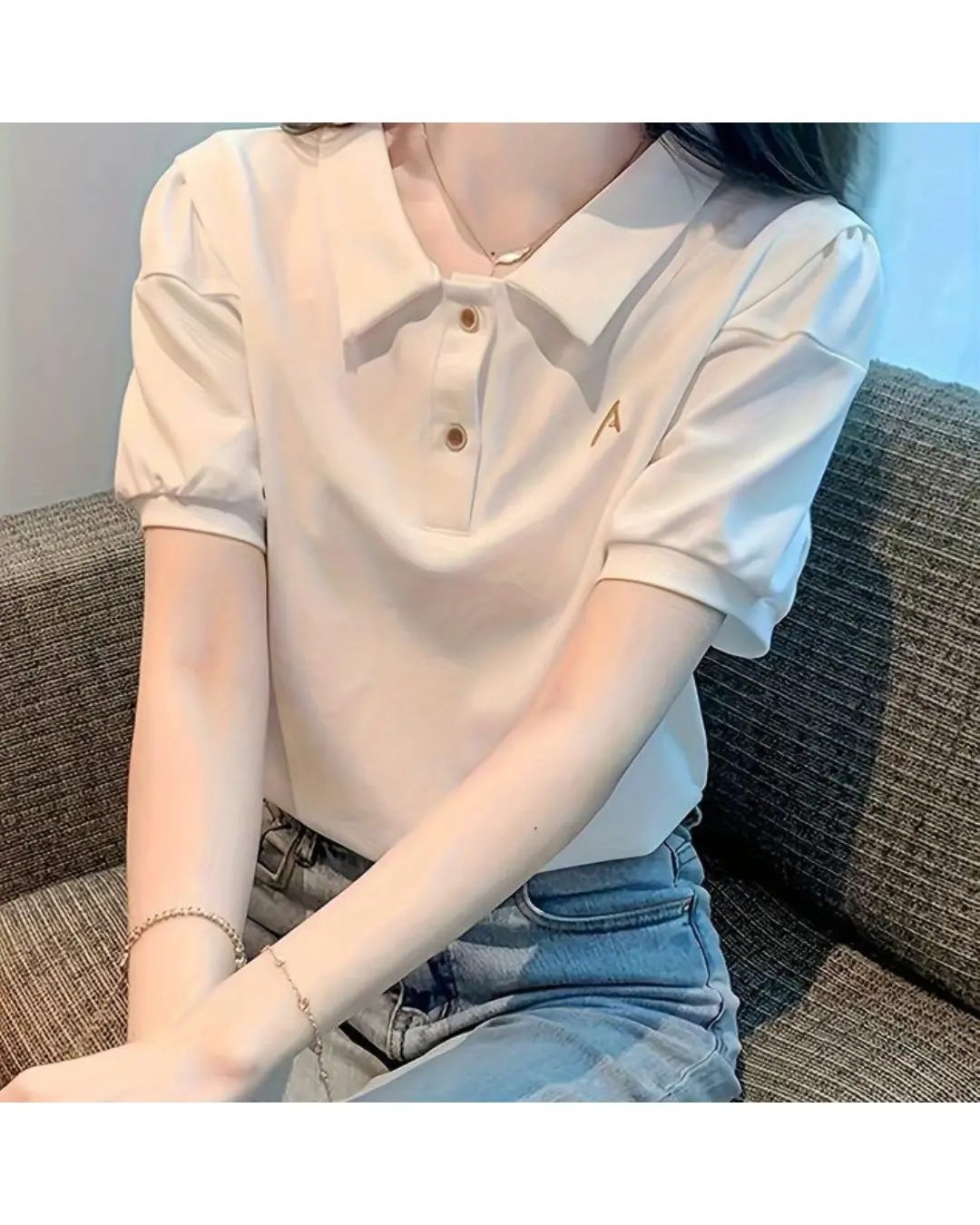 White puff-sleeve polo top with button placket worn by a woman