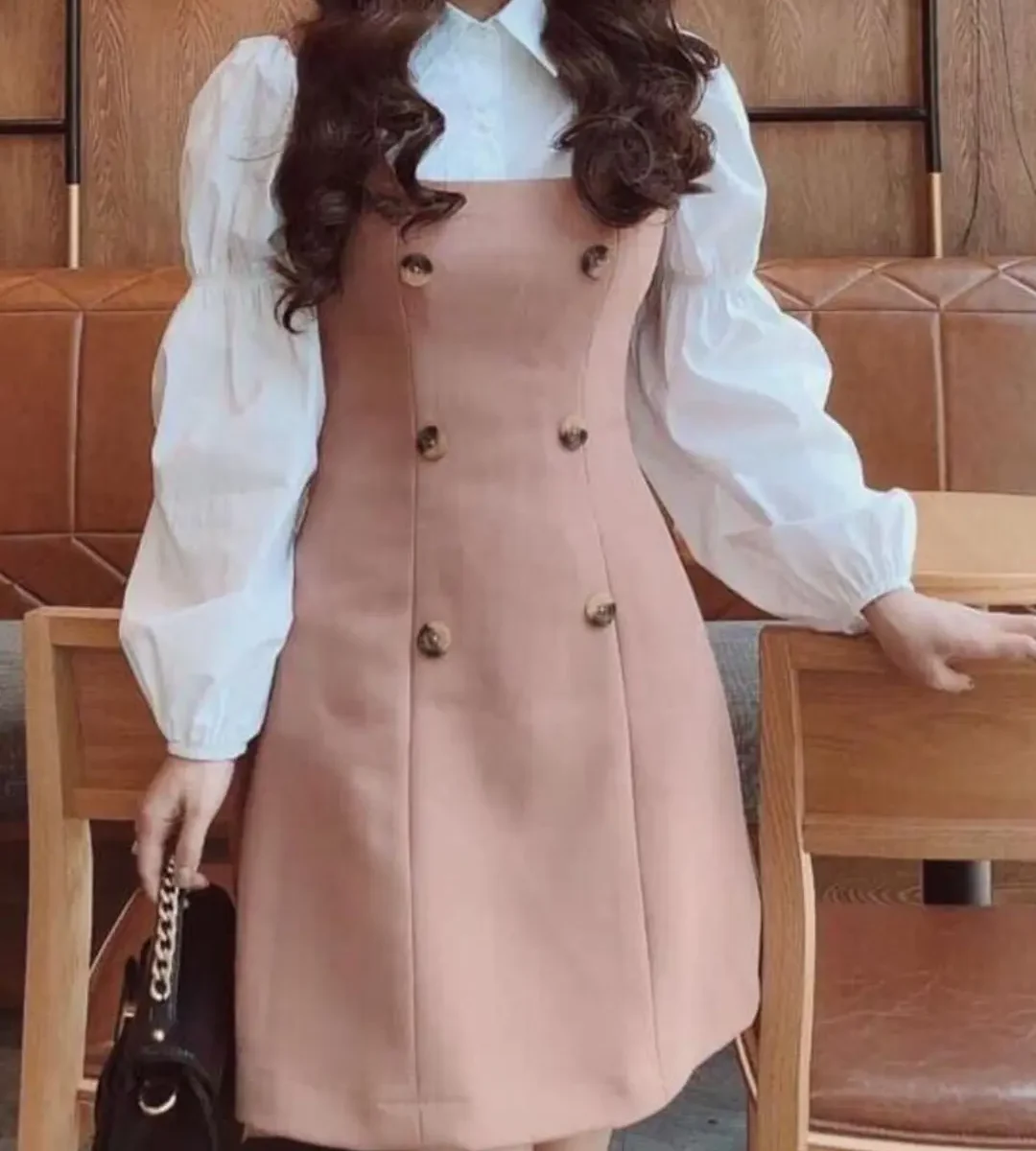 Blush pink sleeveless button-front dress layered over a white puff-sleeve blouse