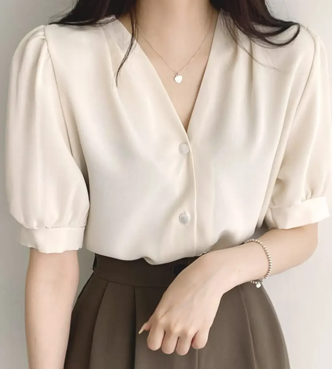 Elegant cream puff-sleeve blouse with button front worn by a woman
