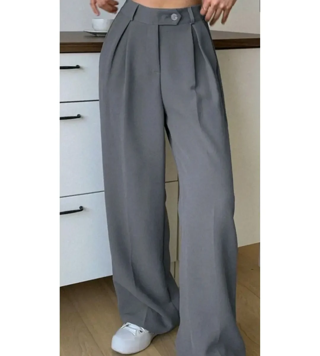 Grey high-waisted wide-leg trousers with pleated front worn by a woman