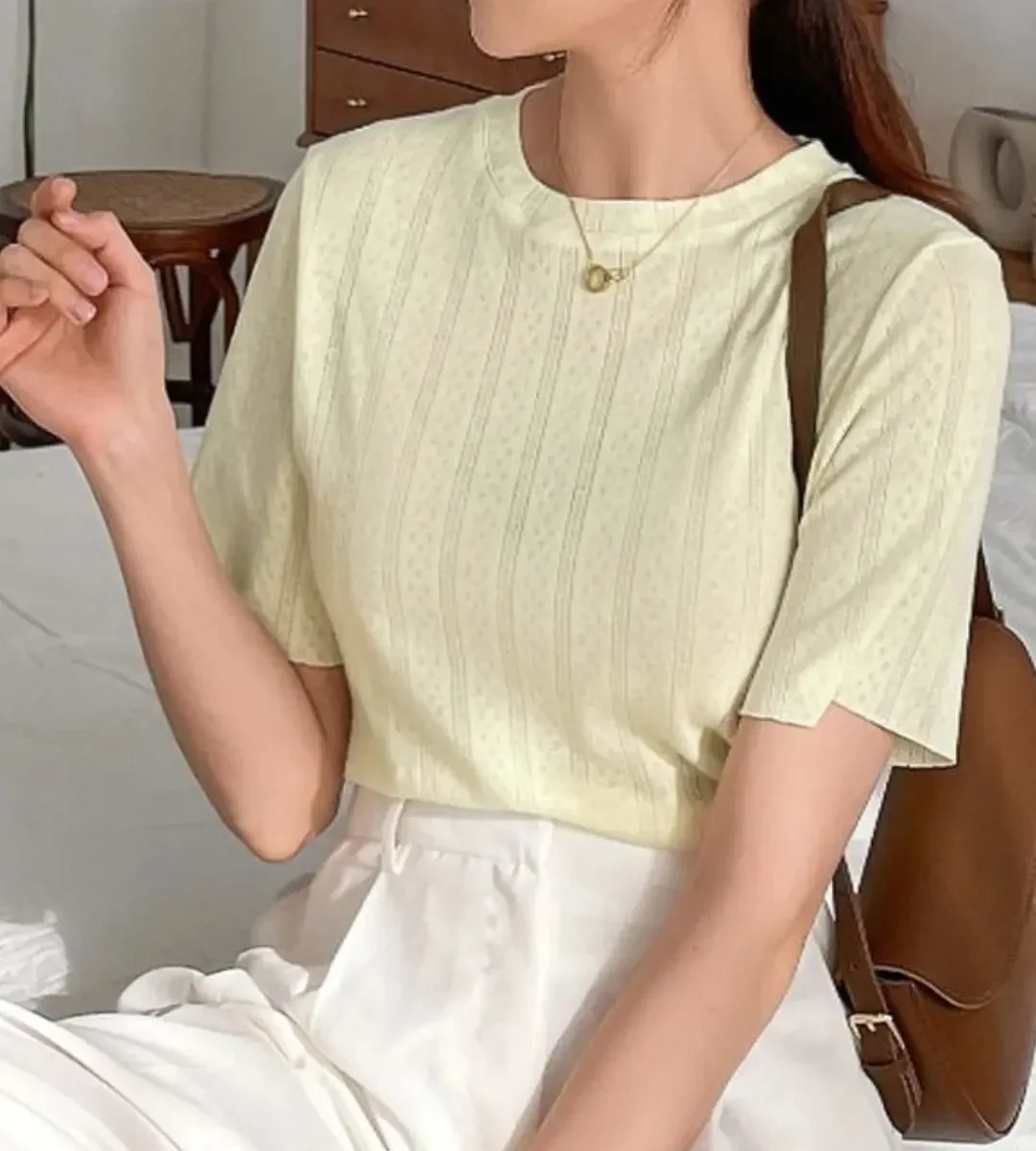 Light yellow round-neck short-sleeve top worn by a woman indoors