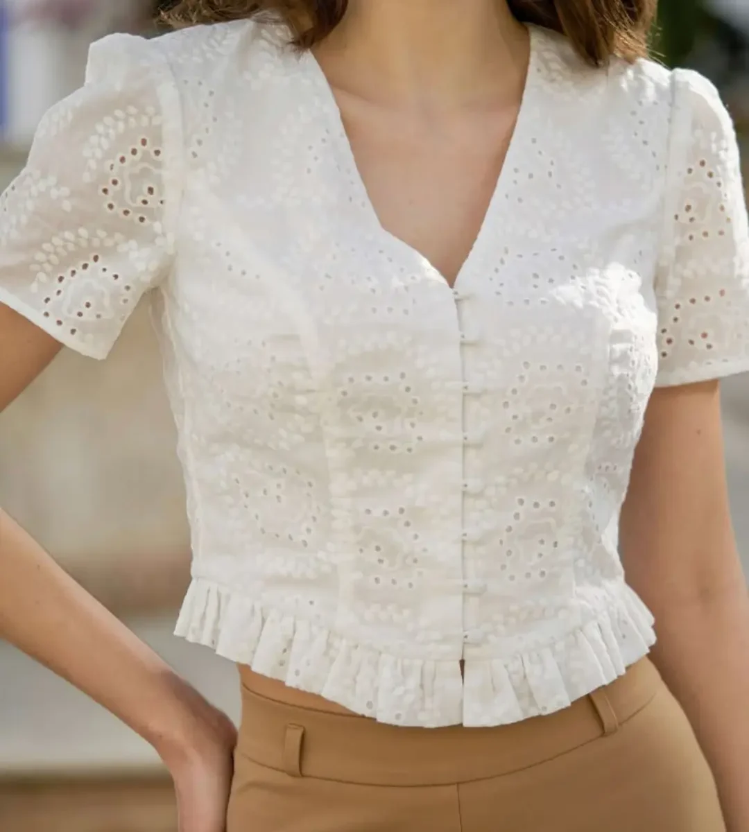 White embroidered short-sleeve blouse with ruffle hem worn by a woman